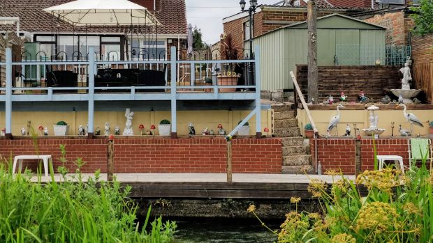 Back garden in Allbrook, with decking, steps down to the canal and lots of statuettes